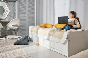 a girl sitting on a bed with a laptop