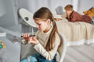 una giovane ragazza seduta su una sedia che tiene in mano un piccolo oggetto