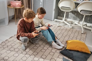 a couple of kids sitting on top of a rug