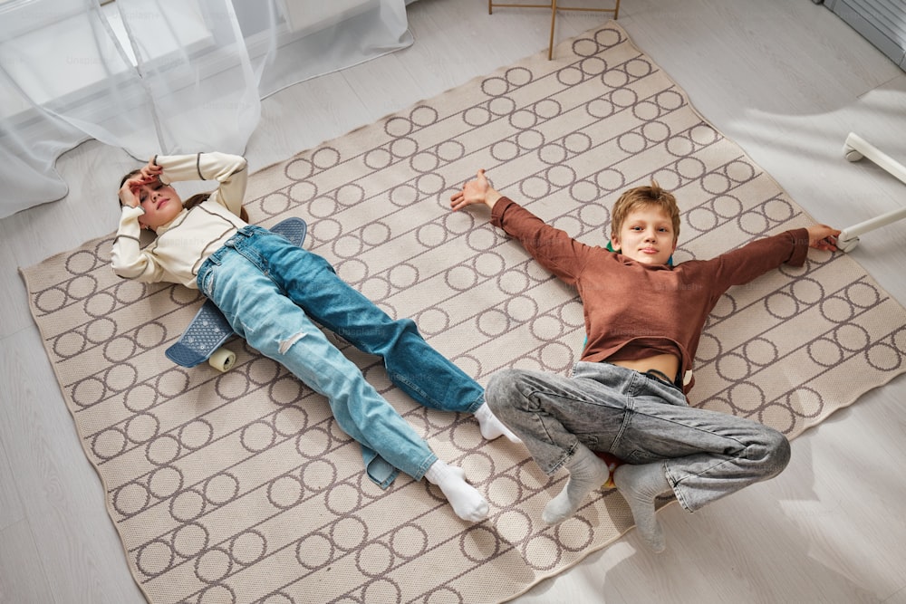 a couple of kids laying on top of a rug