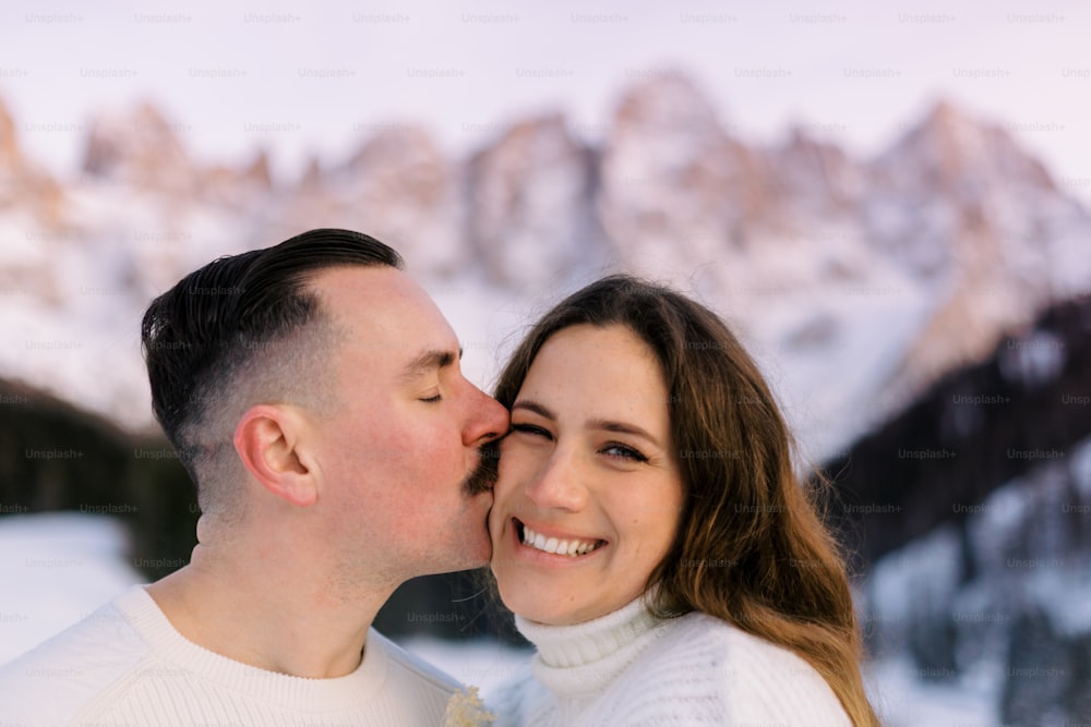 Um homem e uma mulher estão se beijando na neve