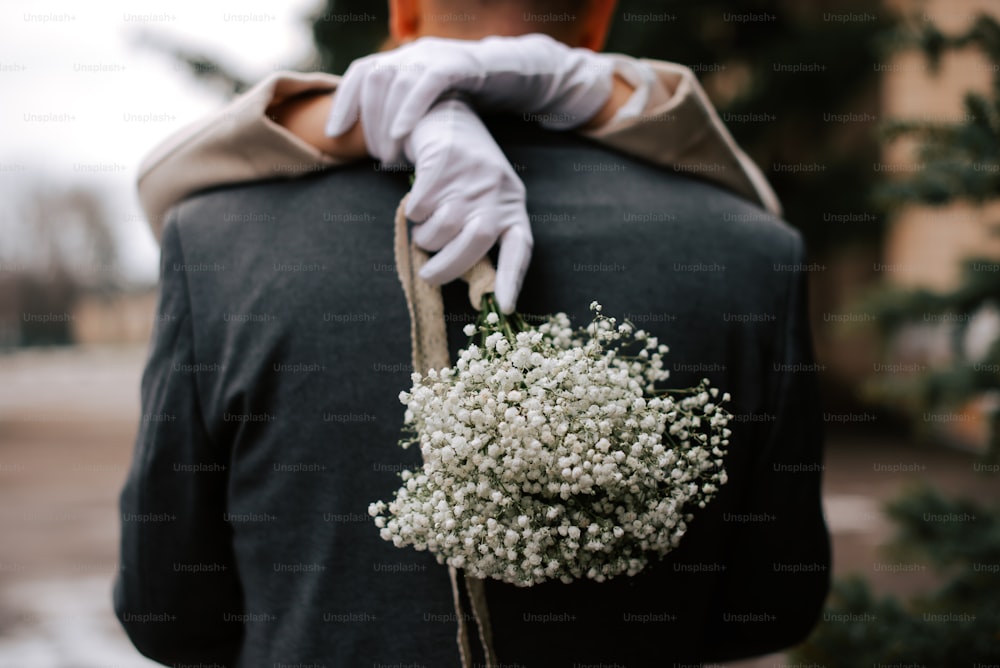 a person in white gloves holding a bouquet of flowers