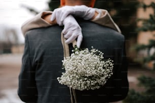 a person in white gloves holding a bouquet of flowers