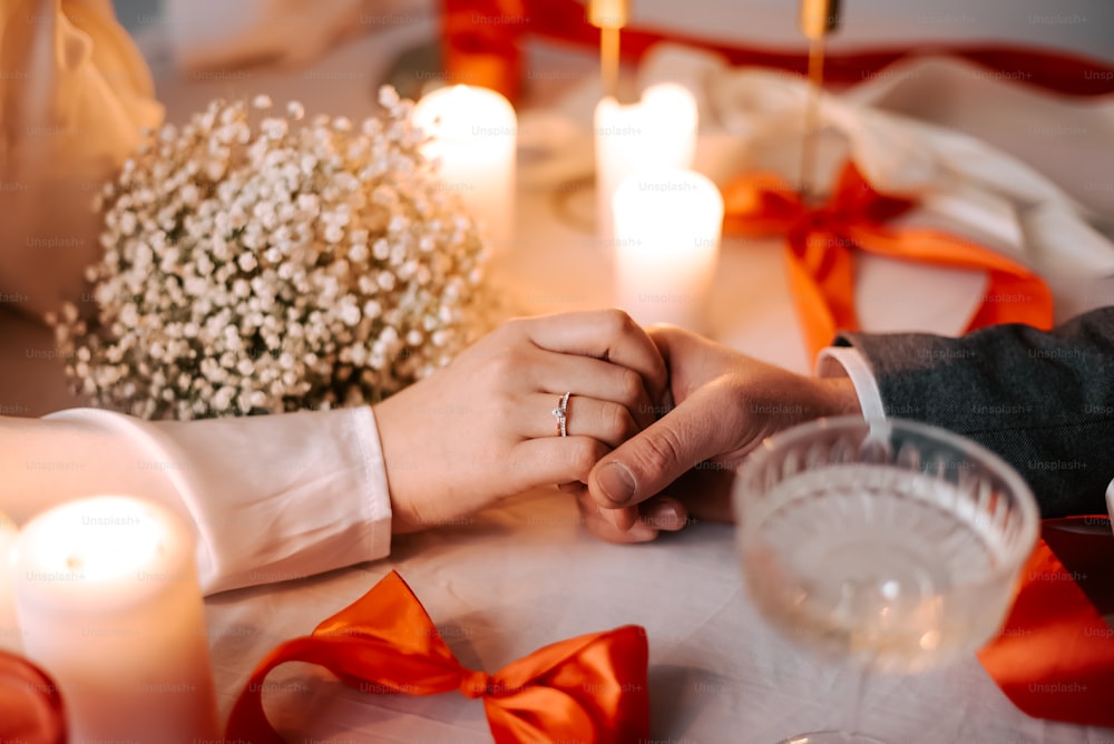 a close up of two people holding hands at a table