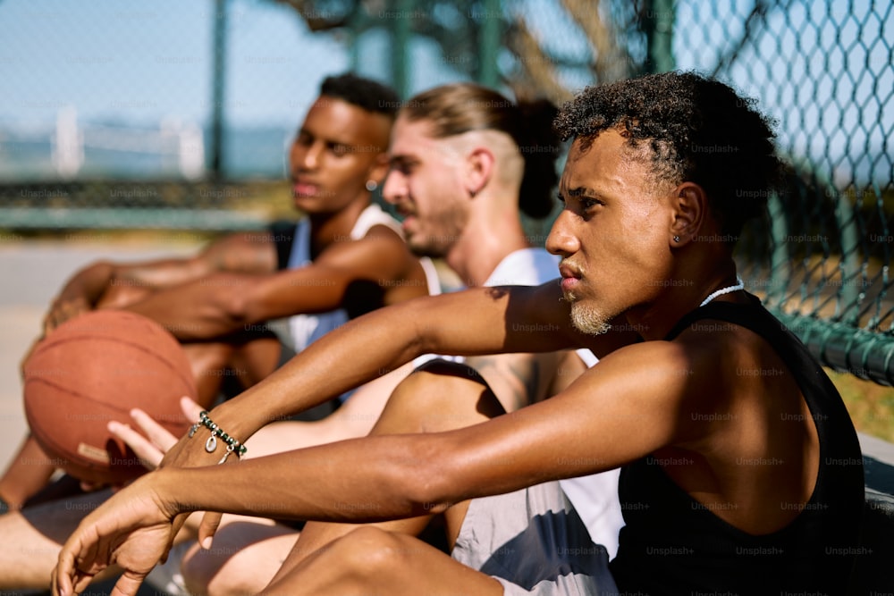 um grupo de homens sentados em um banco com uma bola de basquete