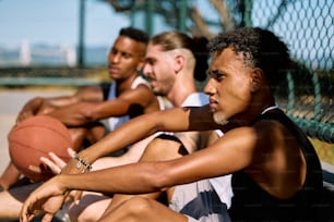 a group of men sitting on a bench with a basketball
