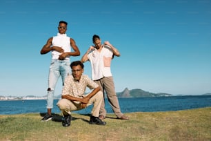 three men posing for a picture in front of a body of water