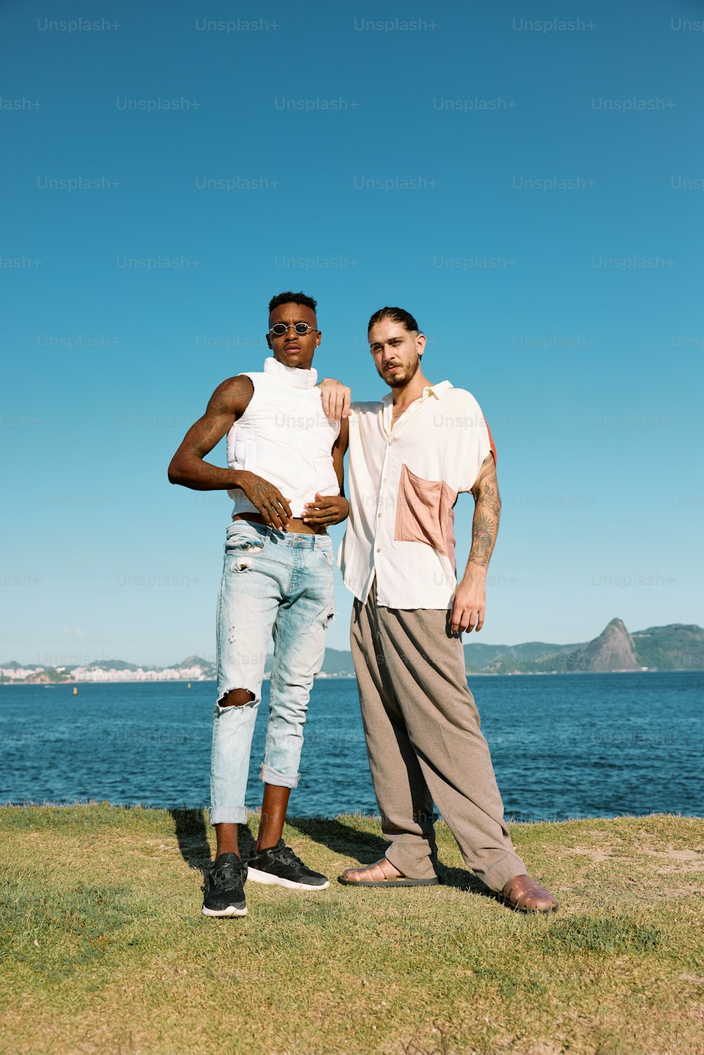 two men standing next to each other near the water