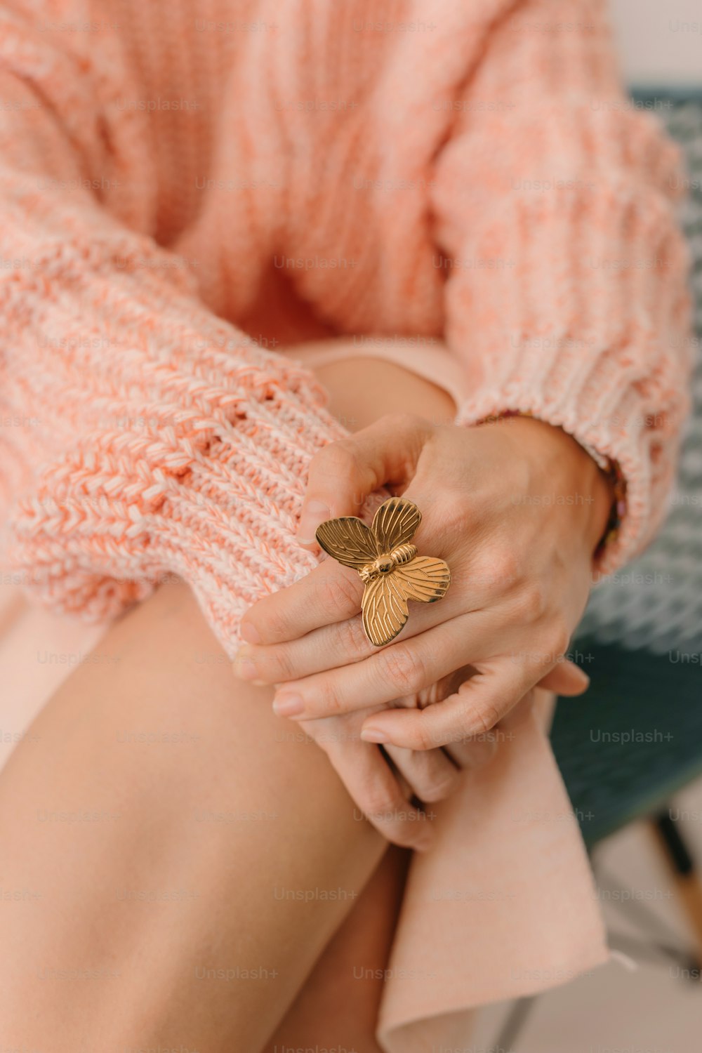 a woman in a pink sweater holding a gold leaf ring
