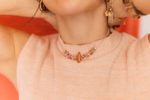 a woman wearing a pink sweater and earrings