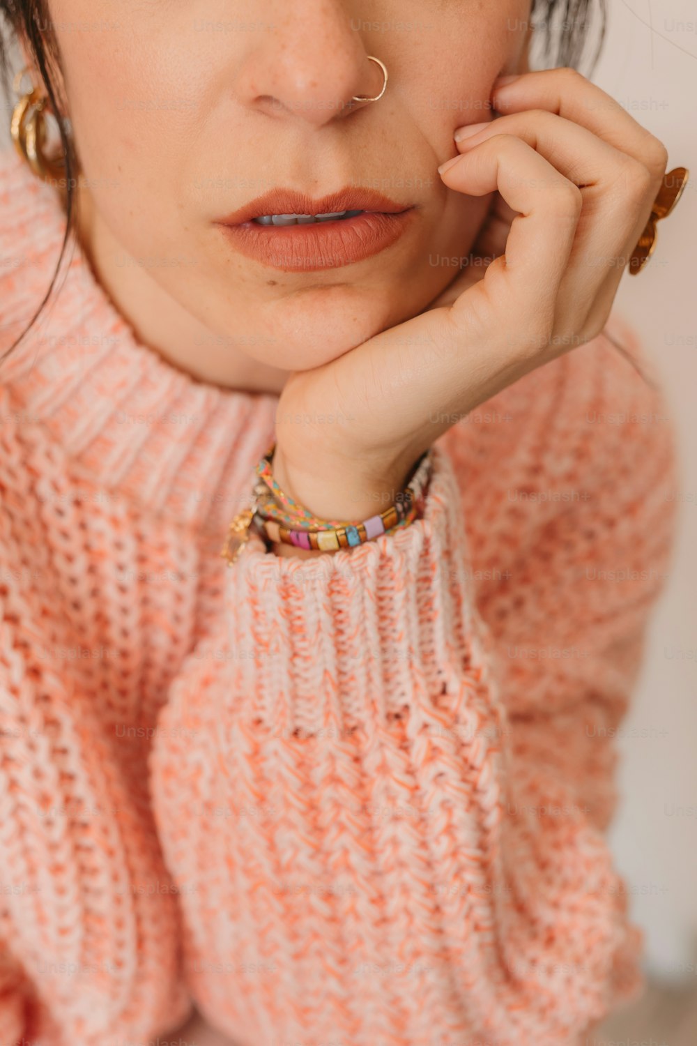 a woman in a pink sweater with a nose piercing