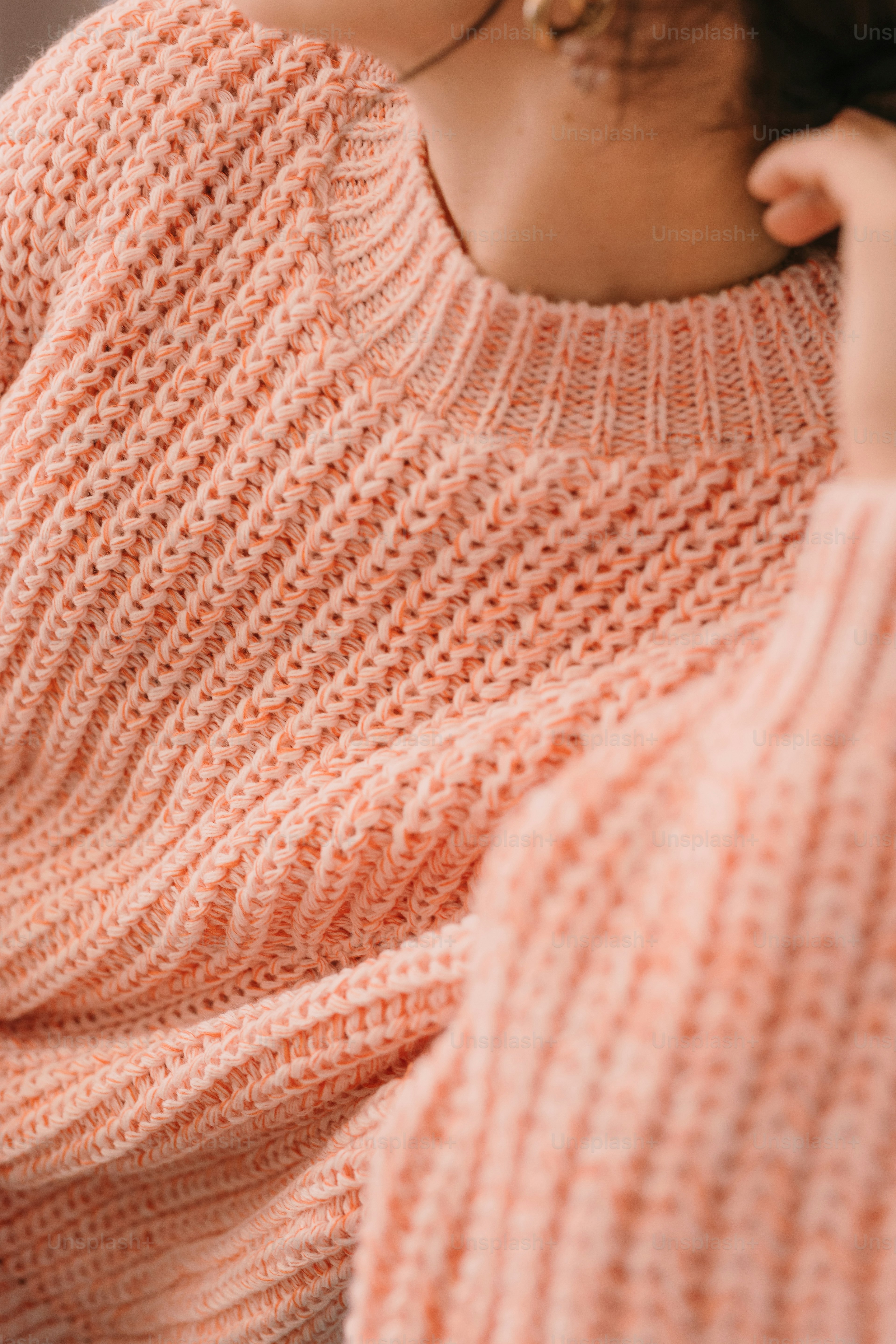 a woman wearing a pink sweater and earrings