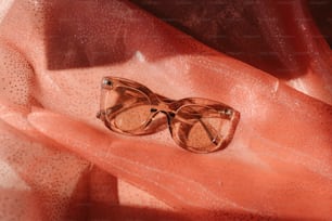 a pair of glasses sitting on top of a pink cloth