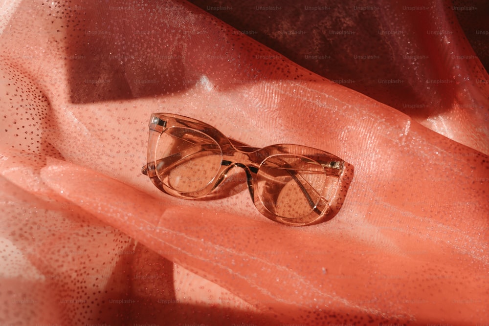 a pair of glasses sitting on top of a pink cloth