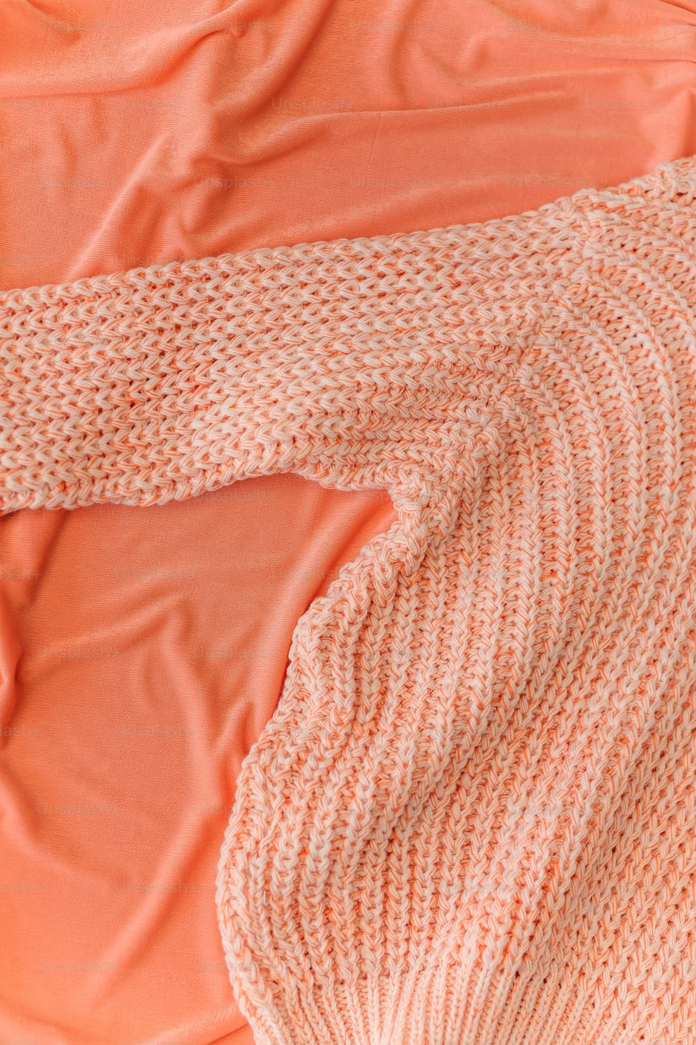 a sweater laying on top of an orange sheet