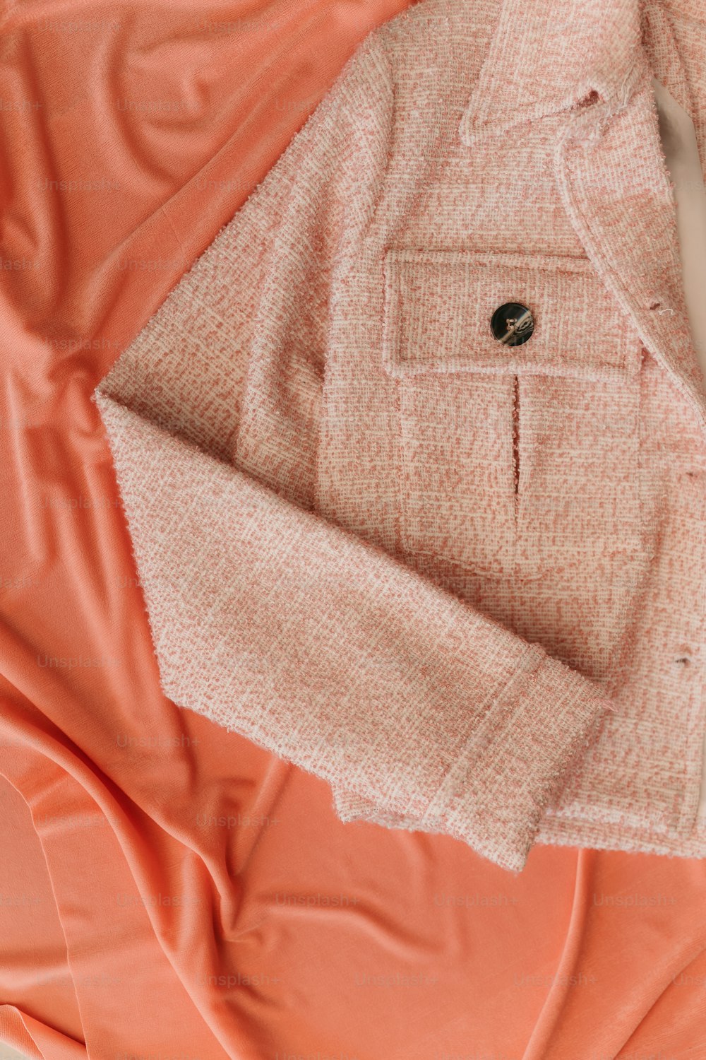 an orange and pink jacket laying on top of a bed