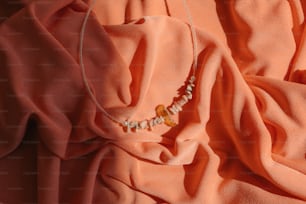a necklace is laying on a pink cloth