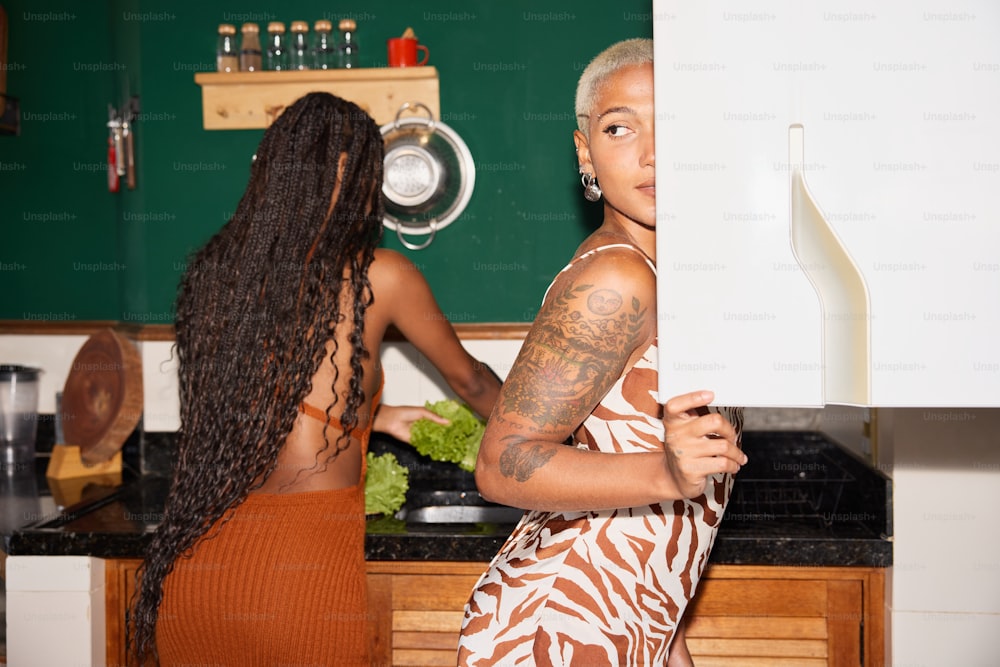 um casal de mulheres em pé em uma cozinha ao lado do outro