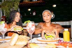 um casal de mulheres sentadas em uma mesa com um sanduíche