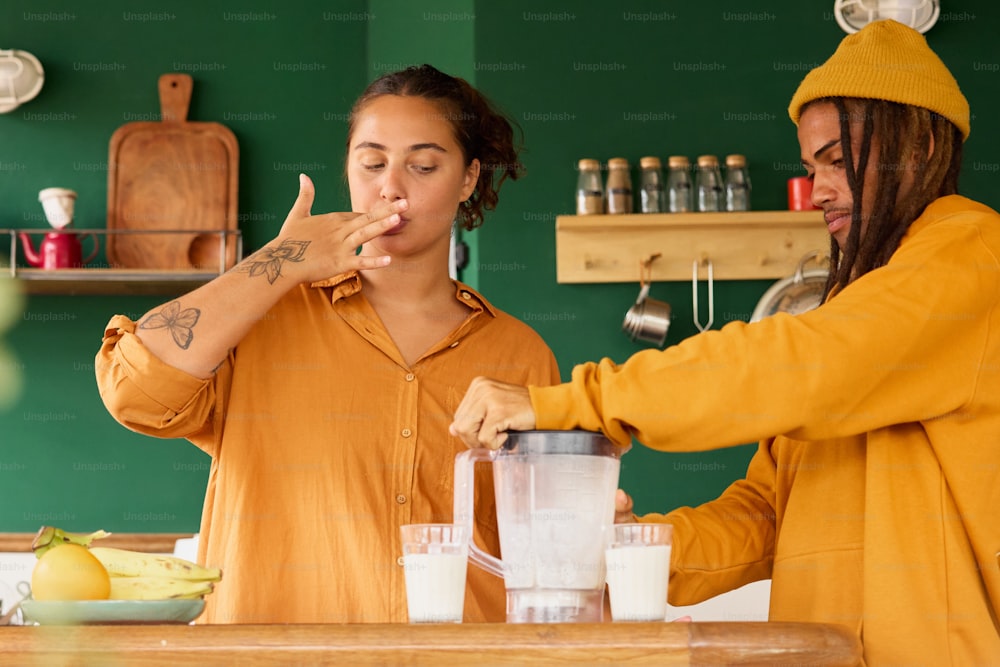 two women in a kitchen making smoothies with a blender