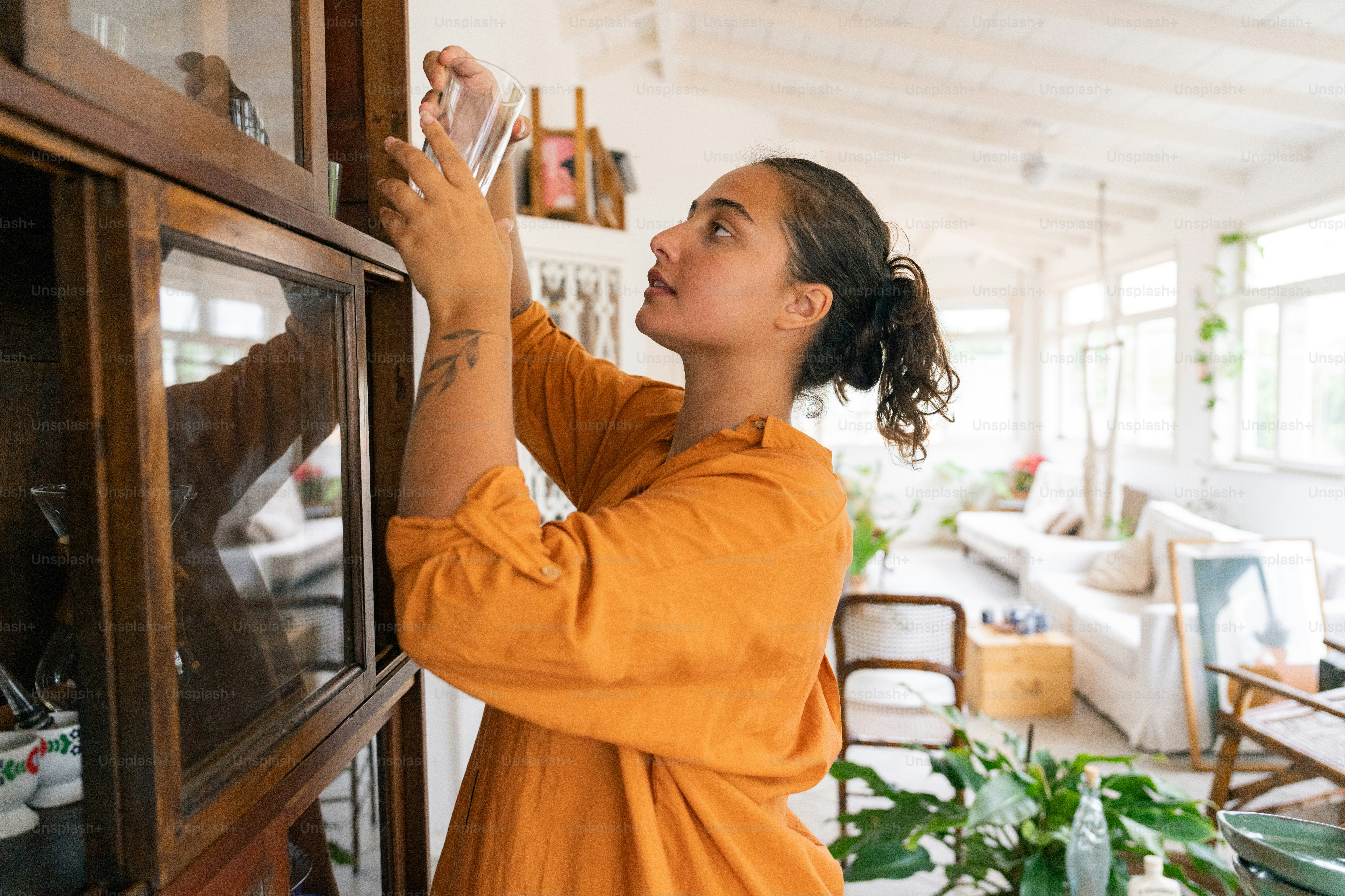 a woman in an orange shirt is looking at something on the wall