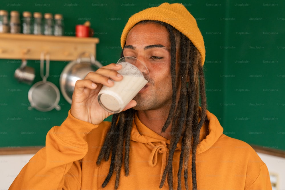 a man with dreadlocks drinking a glass of milk