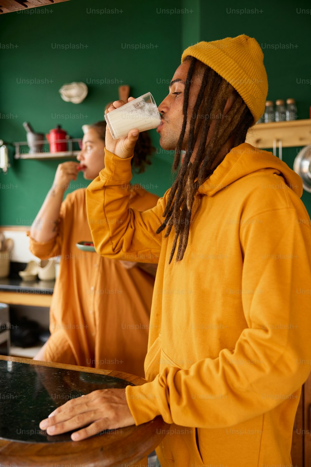 a man with dreadlocks drinking from a glass