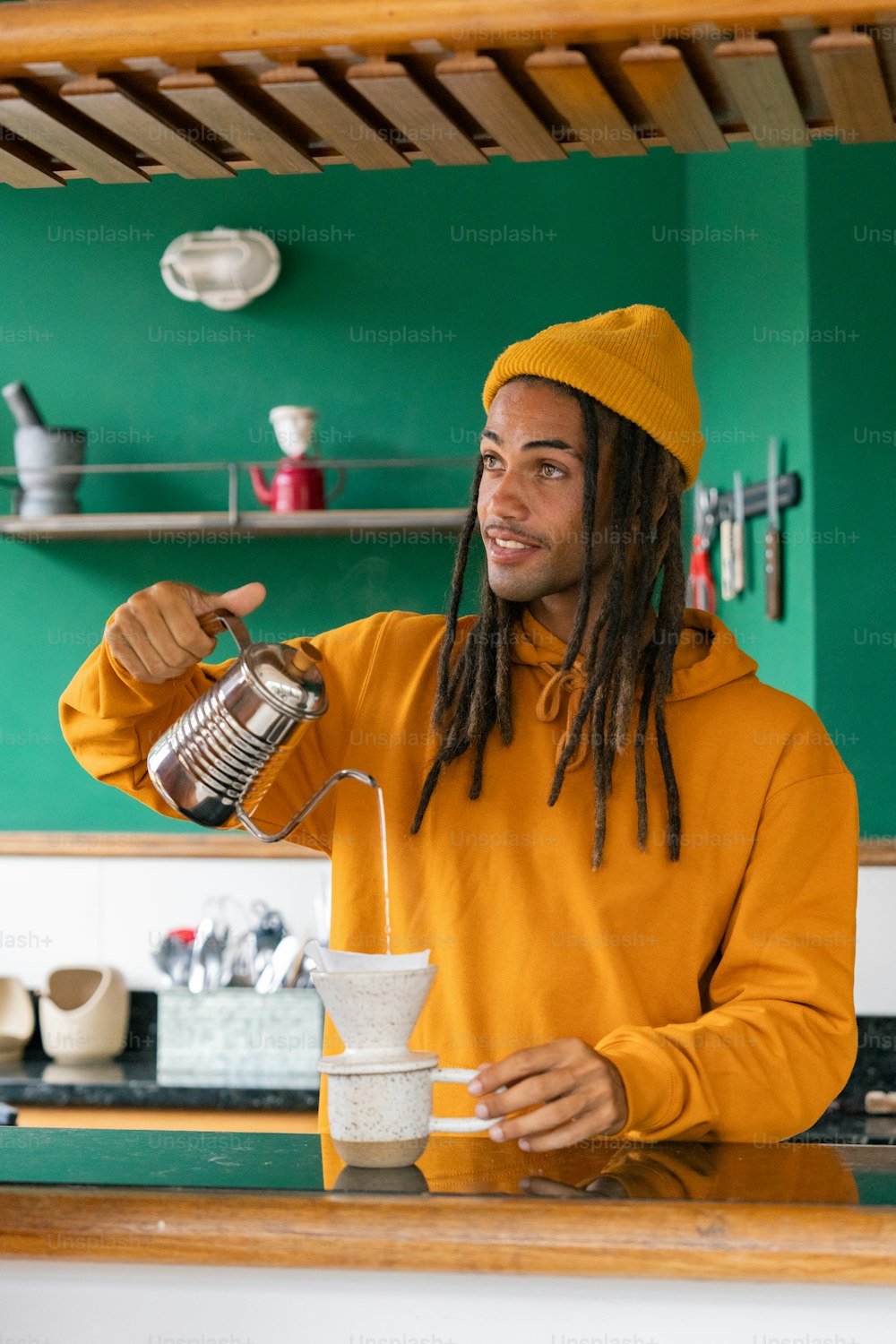 a man with dreadlocks pouring something into a cup