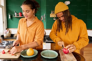 a man and a woman cutting up fruit on a cutting board