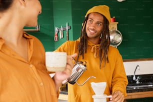 a man with dreadlocks is pouring something into a cup