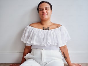 uma mulher sentada no chão com uma tatuagem de borboleta no ombro