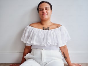 a woman sitting on the floor with a butterfly tattoo on her shoulder