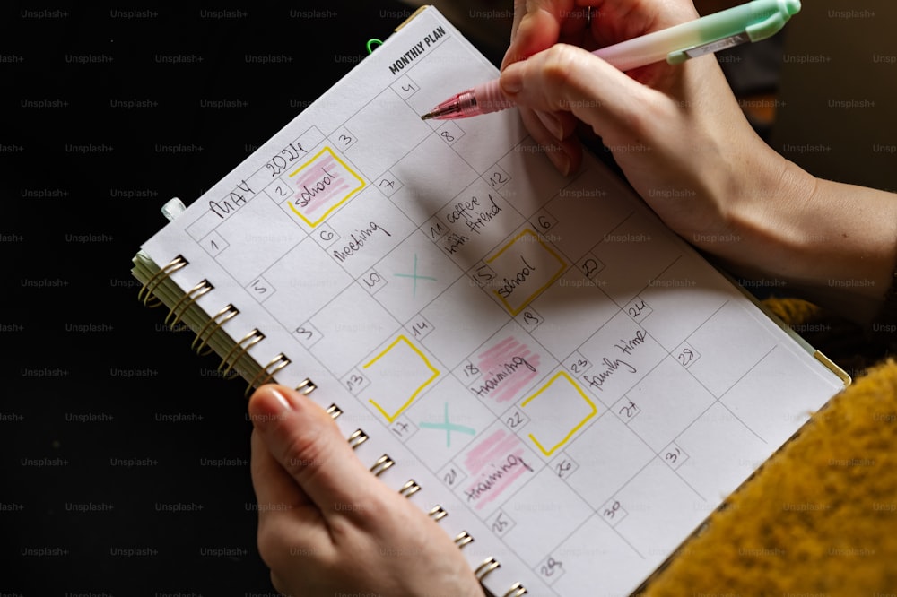 a person holding a pen and writing on a calendar