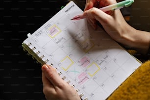a person holding a pen and writing on a calendar