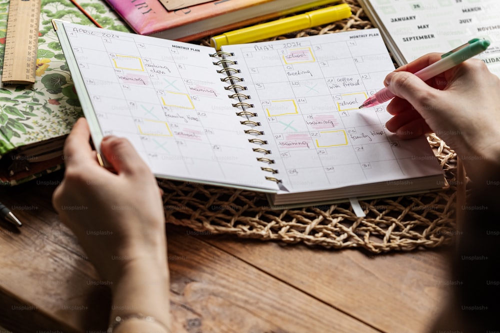 a person holding a pen and looking at a planner