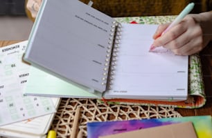 a person writing on a notebook with a pen