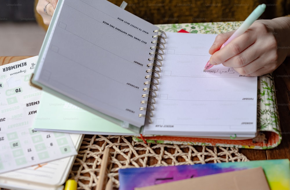 a person writing on a notebook with a pen