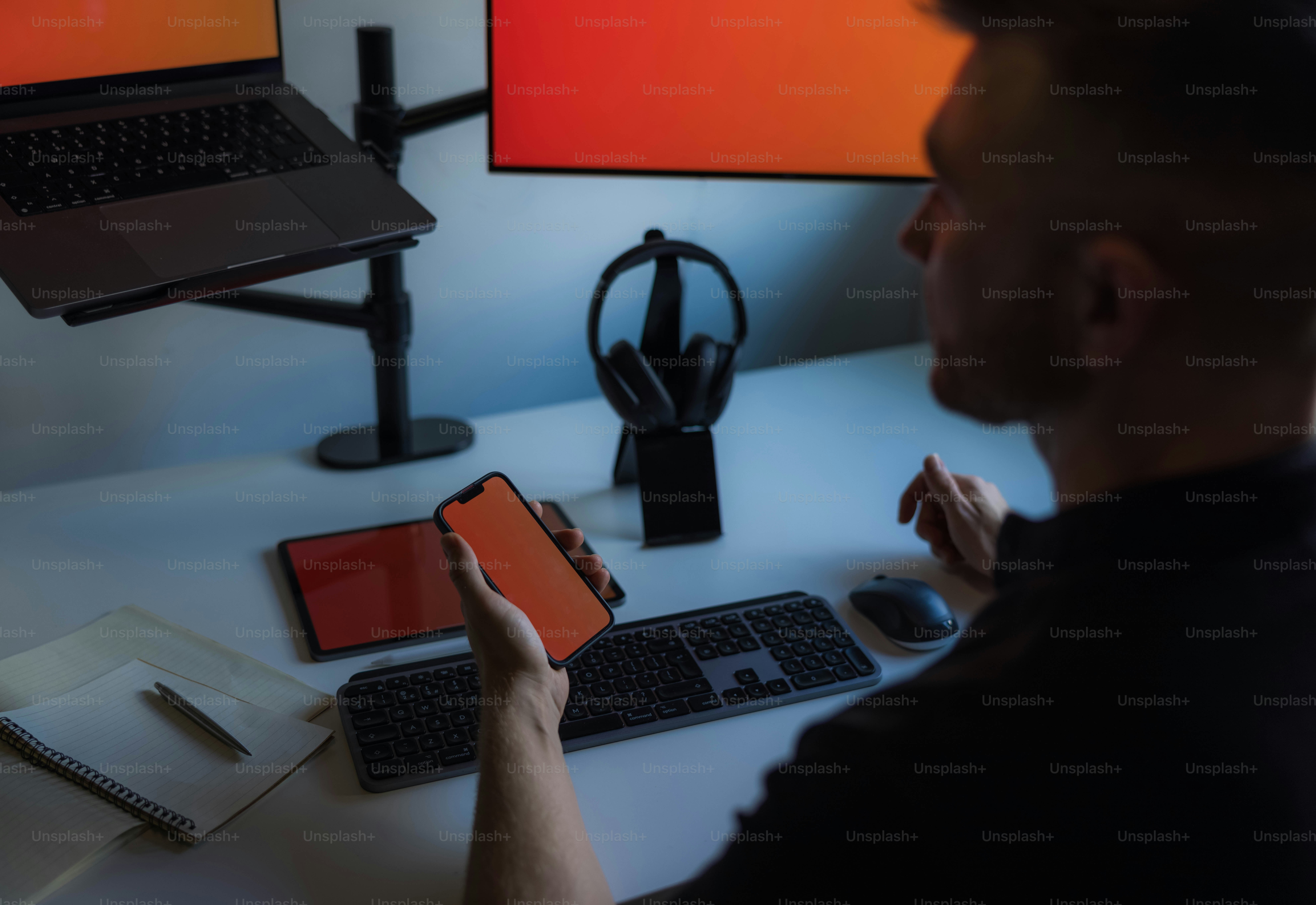 a man sitting at a desk holding a cell phone