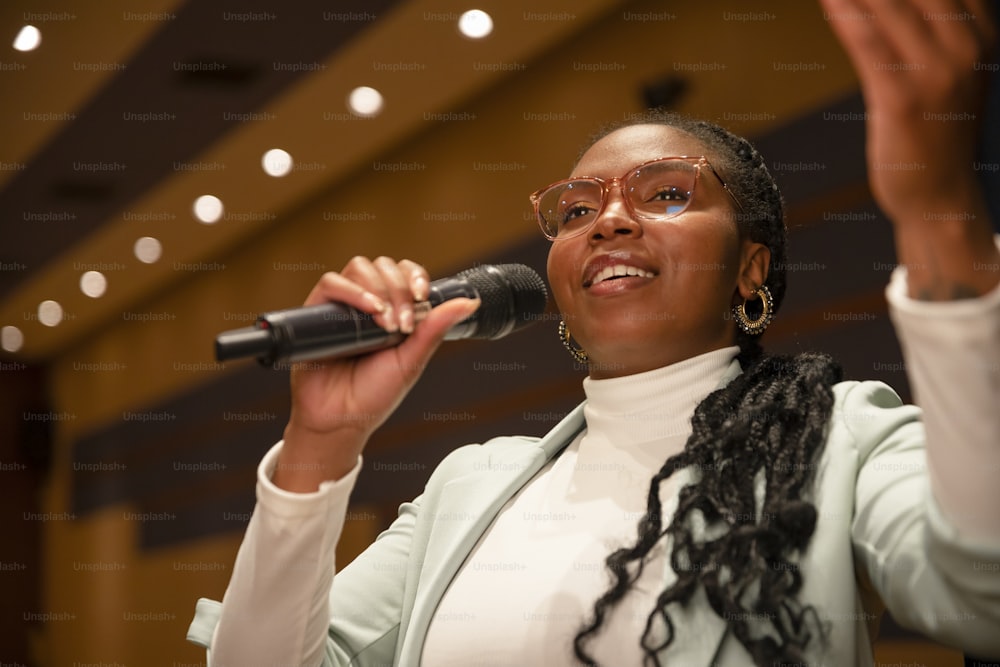 a woman in a white shirt and glasses holding a microphone