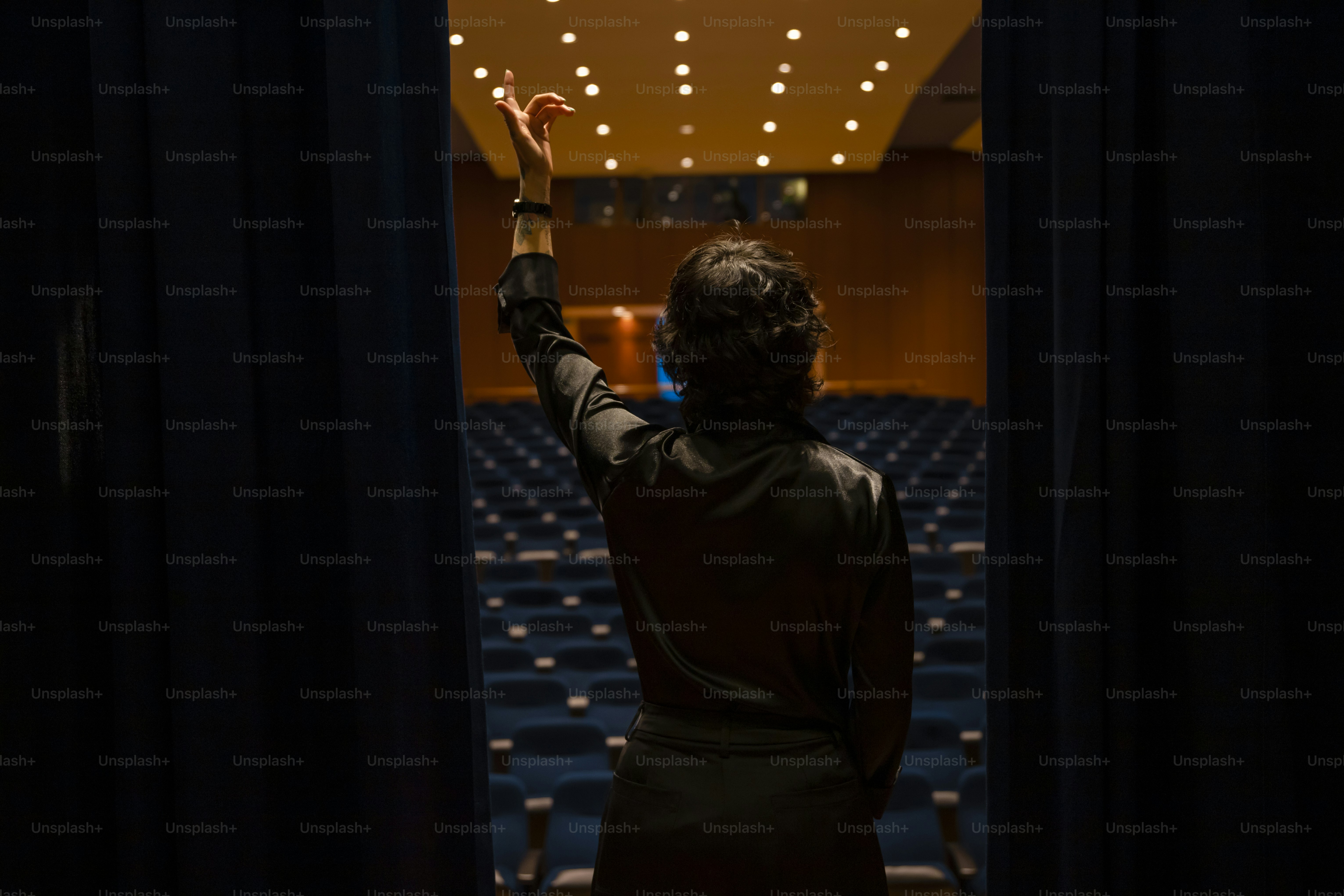 A person standing in front of a stage holding their hands up photo ...