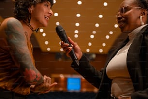a woman holding a microphone talking to another woman