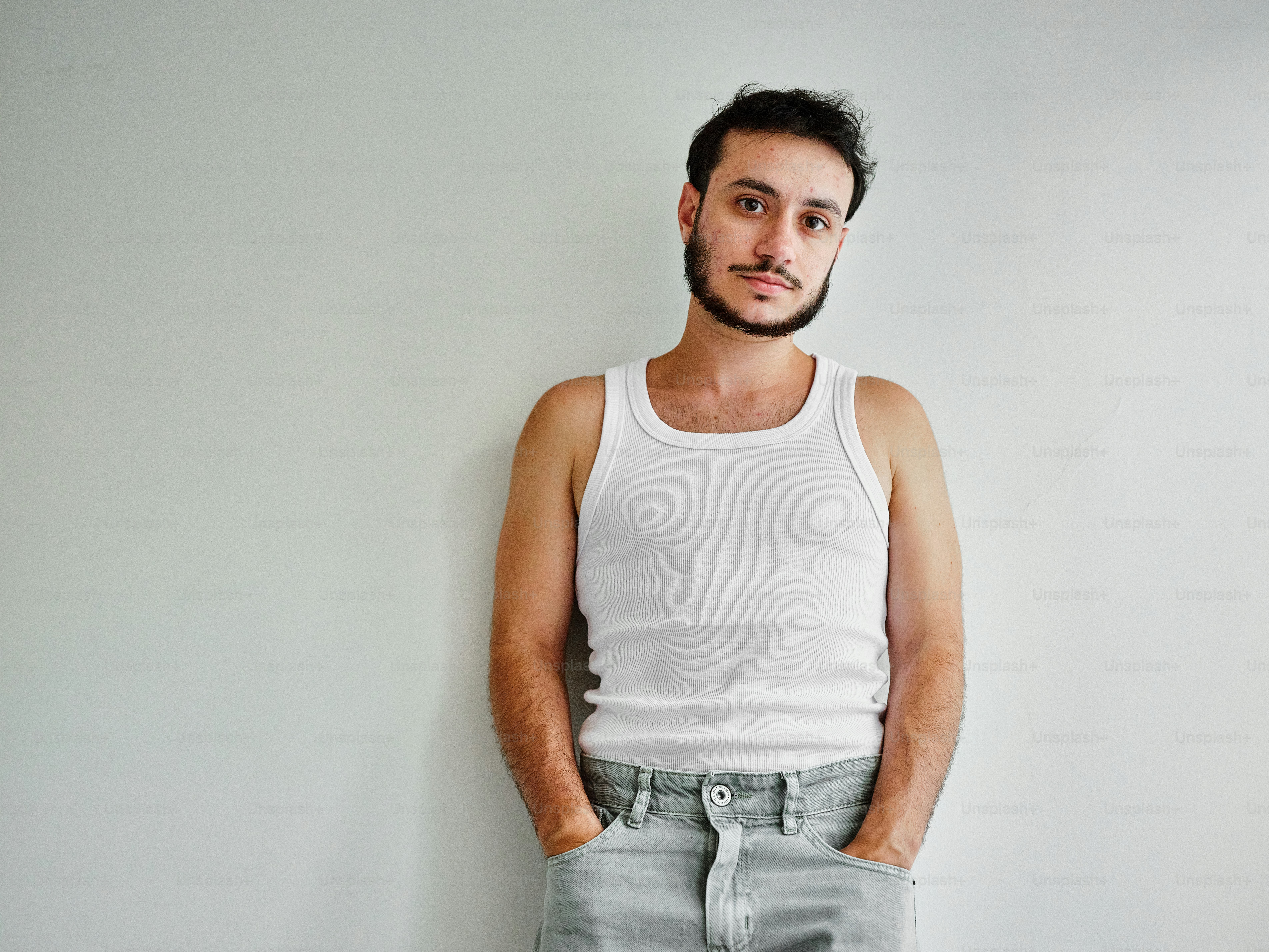 Un hombre parado frente a una pared blanca