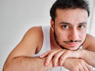 Un hombre con barba de chivo está apoyado en un radiador