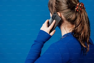 a woman in a blue sweater talking on a cell phone