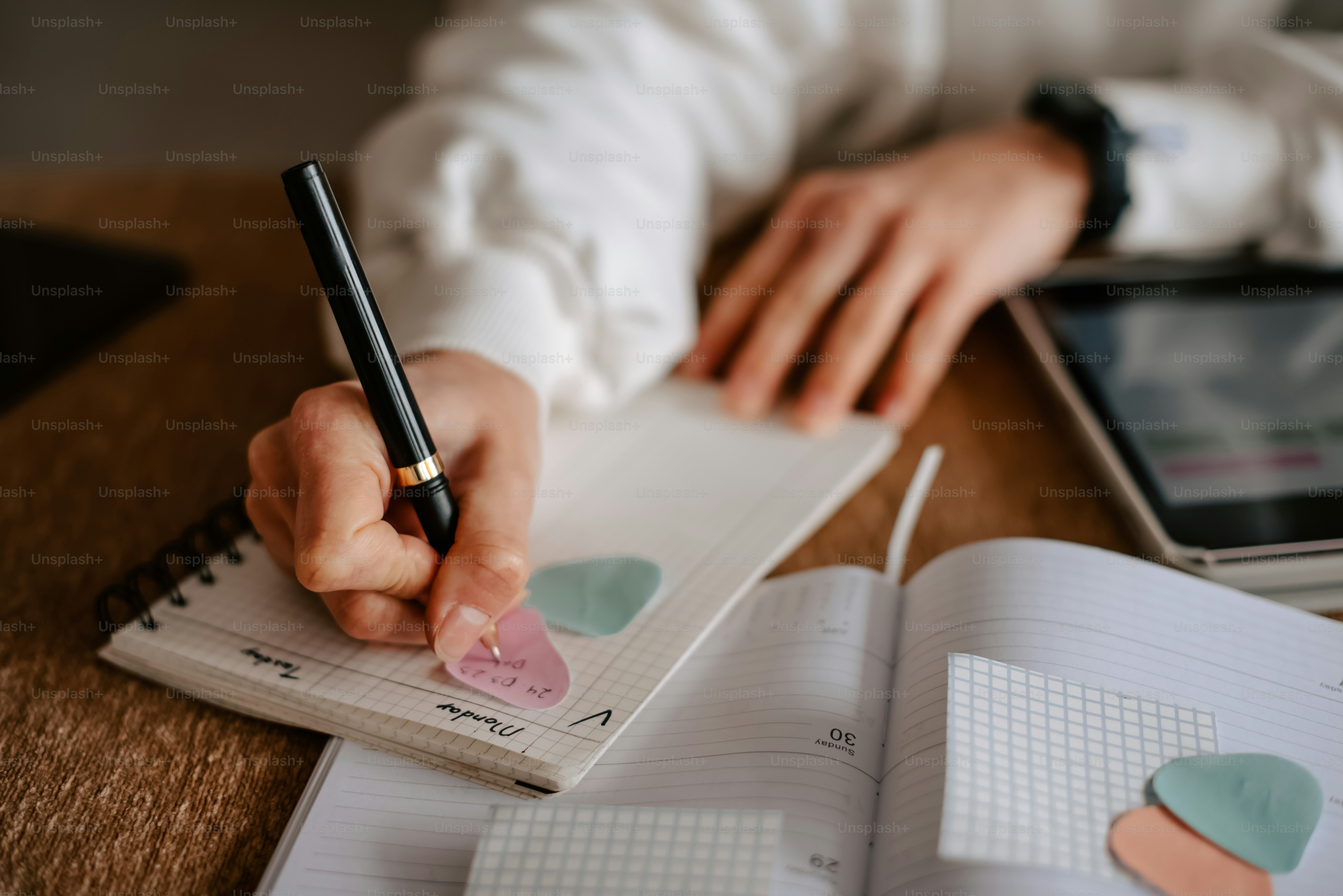 a person writing on a notebook with a pen