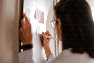 a woman in glasses writing on a white board