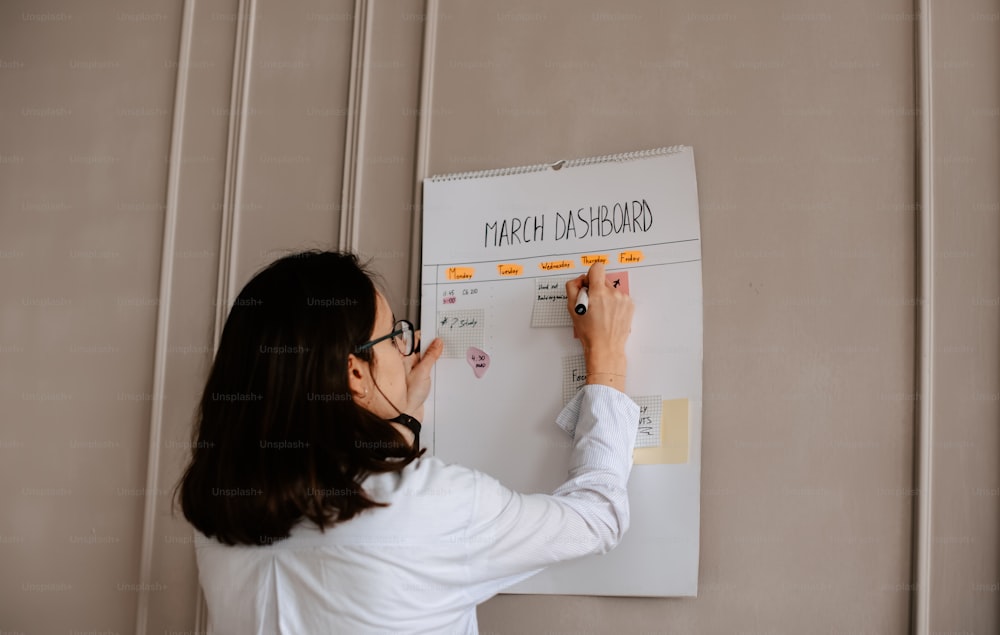 a woman is writing on a white board