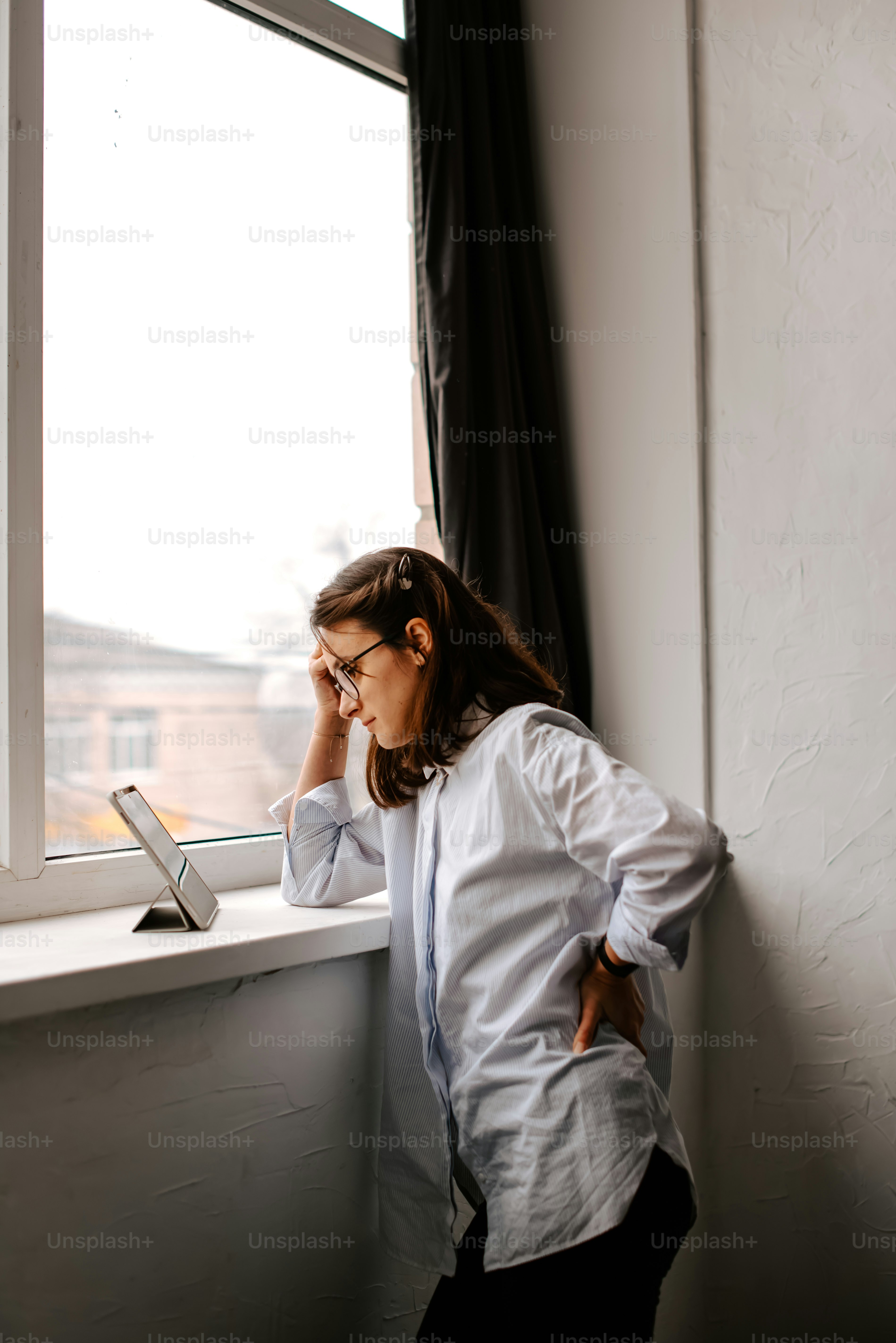 uma mulher encostada no parapeito de uma janela enquanto fala ao celular