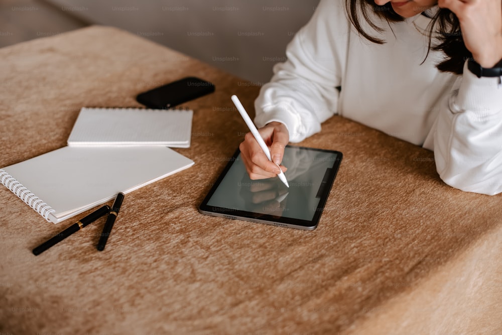 a woman sitting at a table writing on a tablet