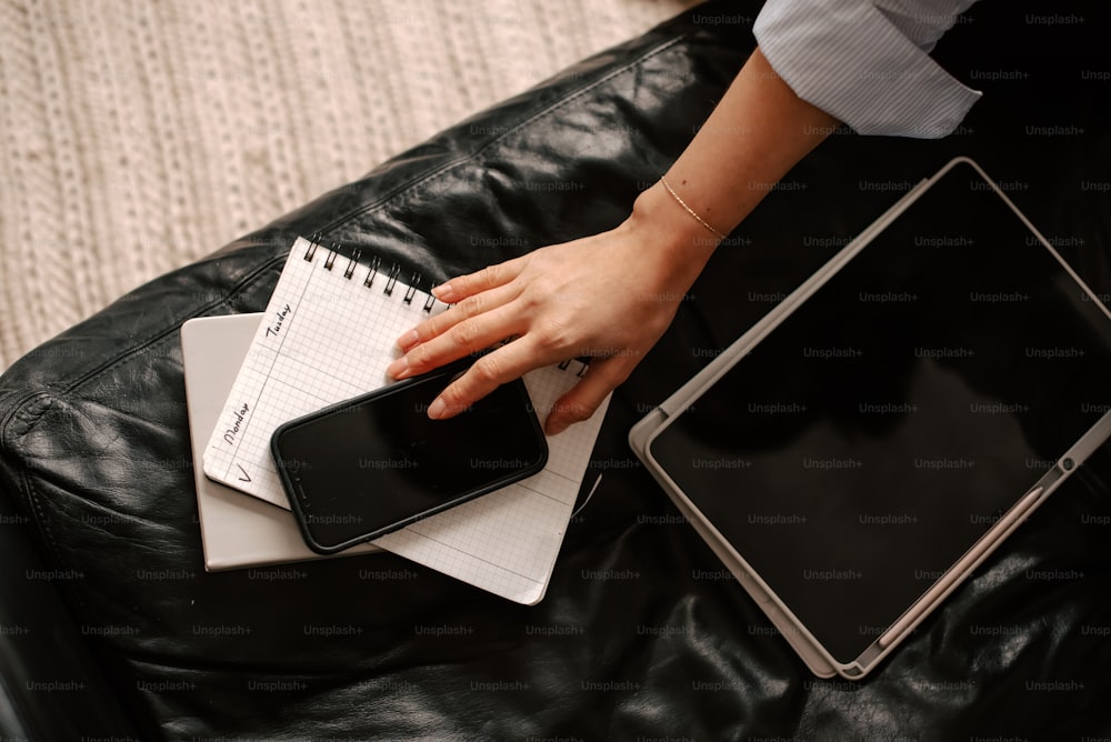 a person holding a cell phone on top of a leather couch